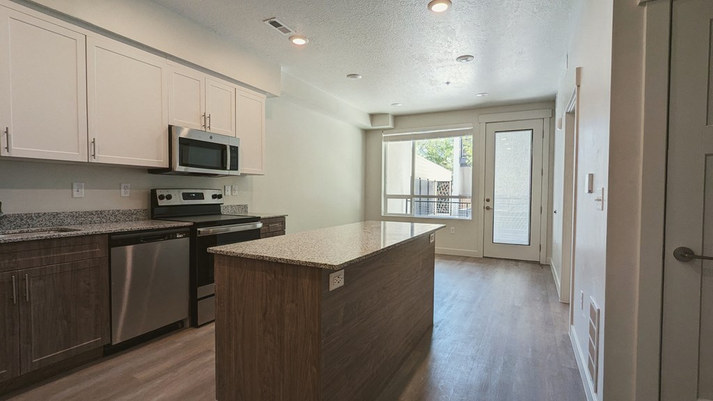 A kitchen with an island and a door leading to a balcony