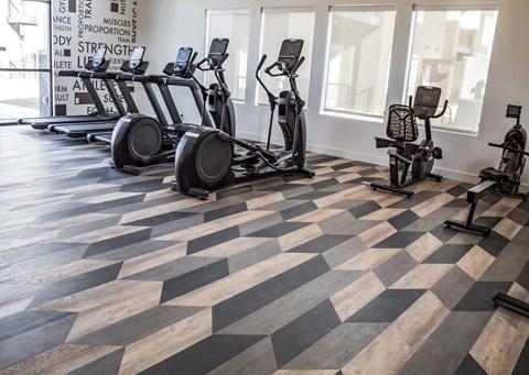 A gym with cardio machines and a checkered floor