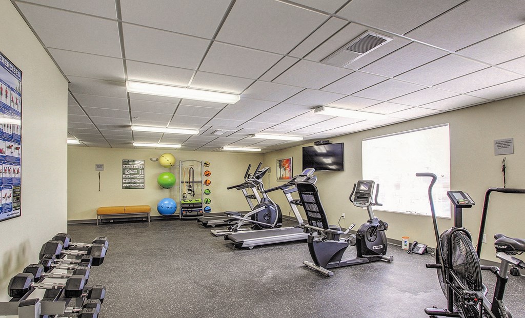 a gym with various exercise equipment and a window