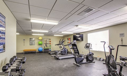 a gym with various exercise equipment and a window