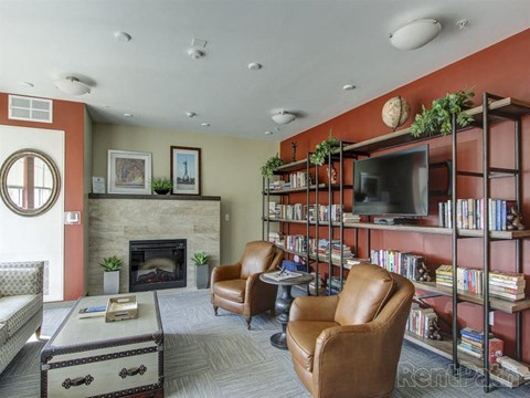 A living room with a fireplace, leather chairs, and a television.