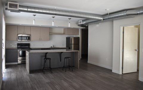 A kitchen with a bar stool and a refrigerator.