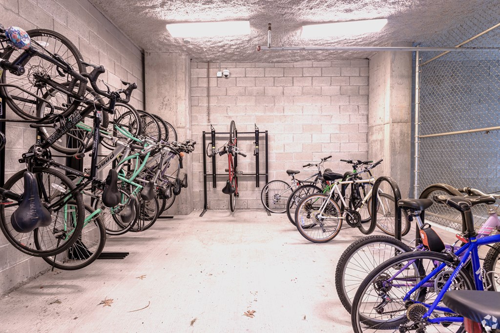 A bike rack full of bicycles in a white brick wall room.