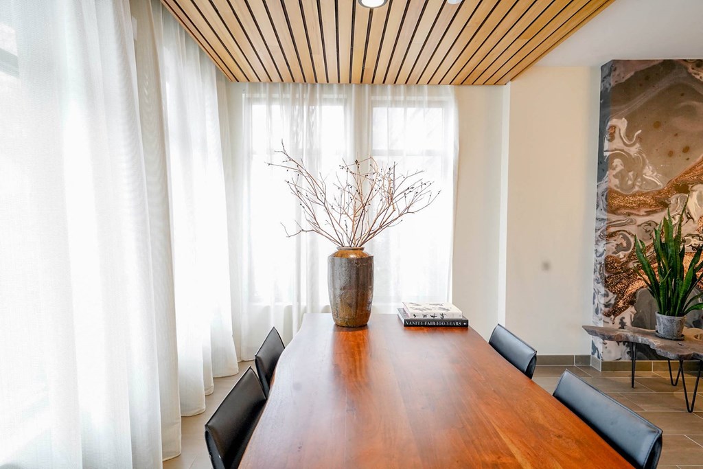 A long wooden table with a vase of dried flowers on it.