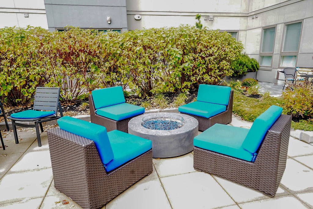 A patio with a fire pit and chairs.