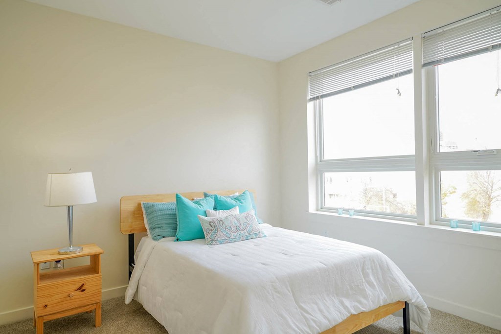 A bedroom with a bed, nightstand, and window.