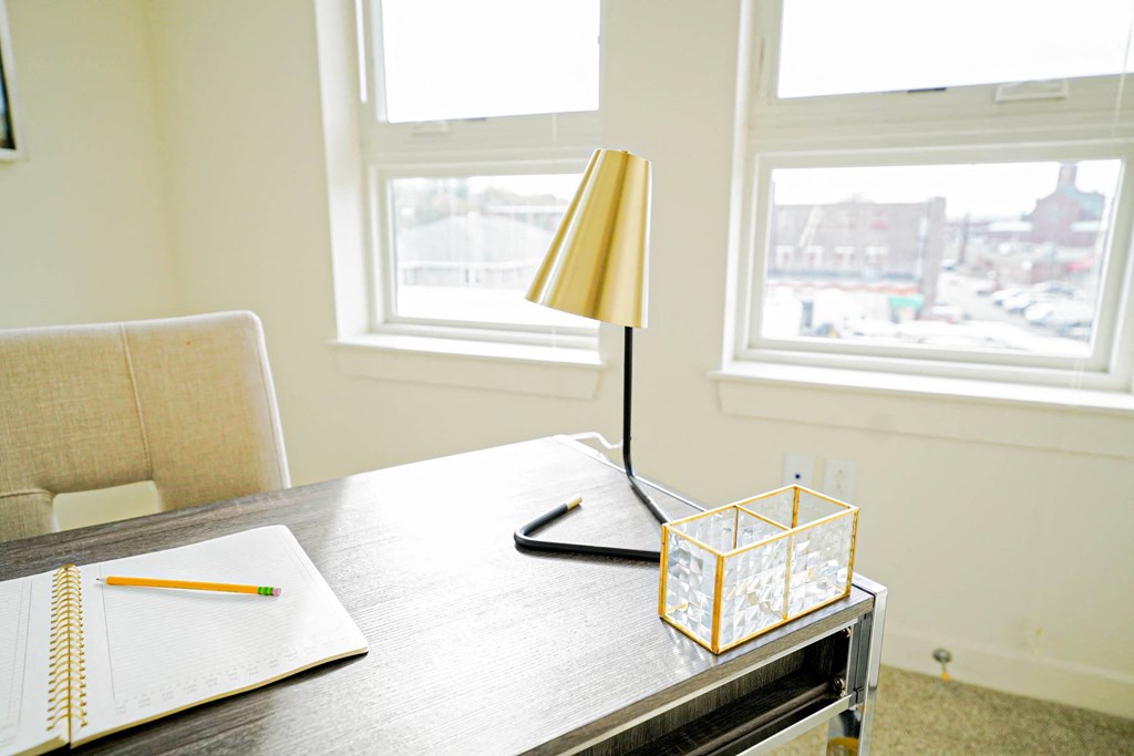 A table with a lamp, a notebook and a pencil on it.