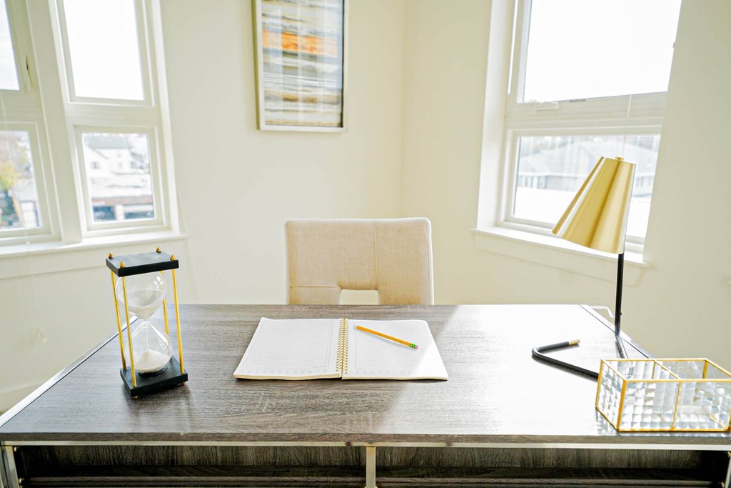 A table with a notebook, pencil, and hourglass on it.