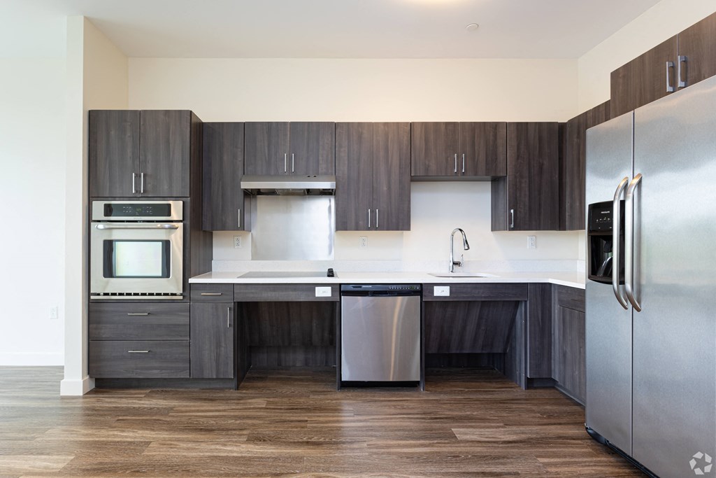 A modern kitchen with dark wood cabinets and stainless steel appliances.