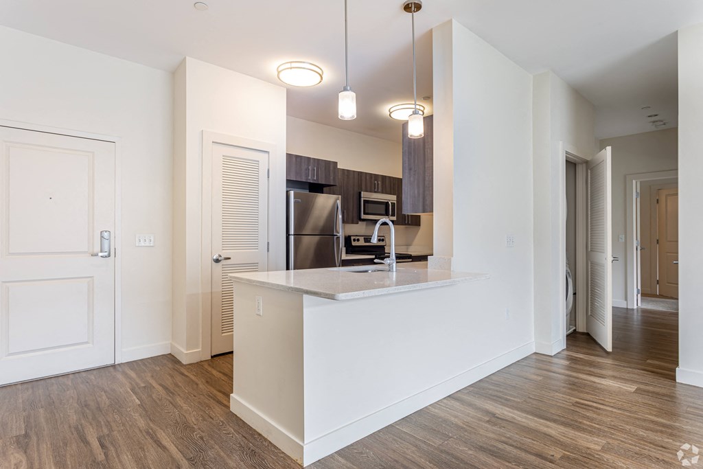 A kitchen with white cabinets and a wooden floor.