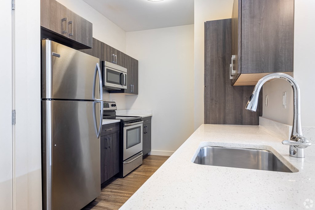 A kitchen with a stainless steel refrigerator, microwave, and sink.