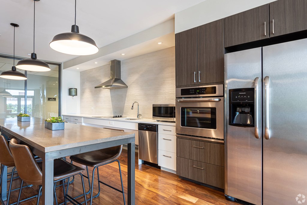 A modern kitchen with a stainless steel refrigerator, oven, and dining table.