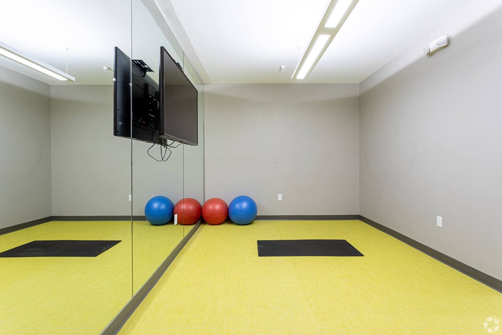 A room with a yellow floor and a television mounted on the wall.