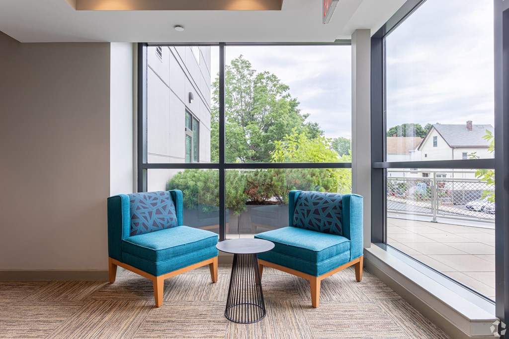 Two blue chairs and a small table in a room with a view of the outside.