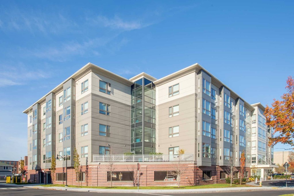 A modern multi-story building with a mix of glass and solid panels.