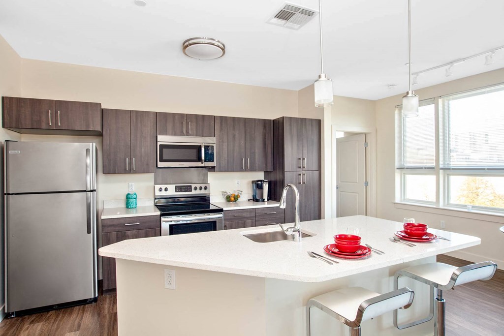 A modern kitchen with a white countertop and stainless steel appliances.