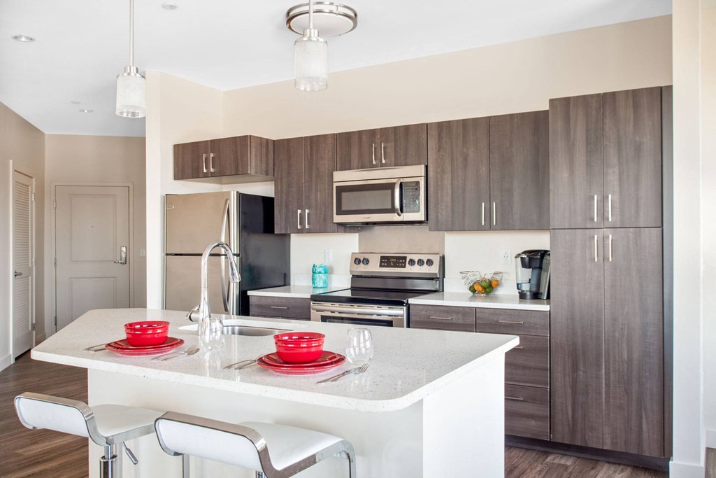 A modern kitchen with a white island and brown cabinets.