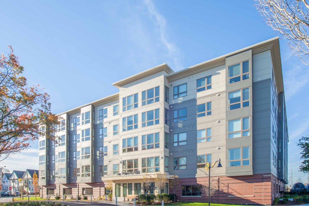 A modern multi-story building with a glass facade and a brick base.