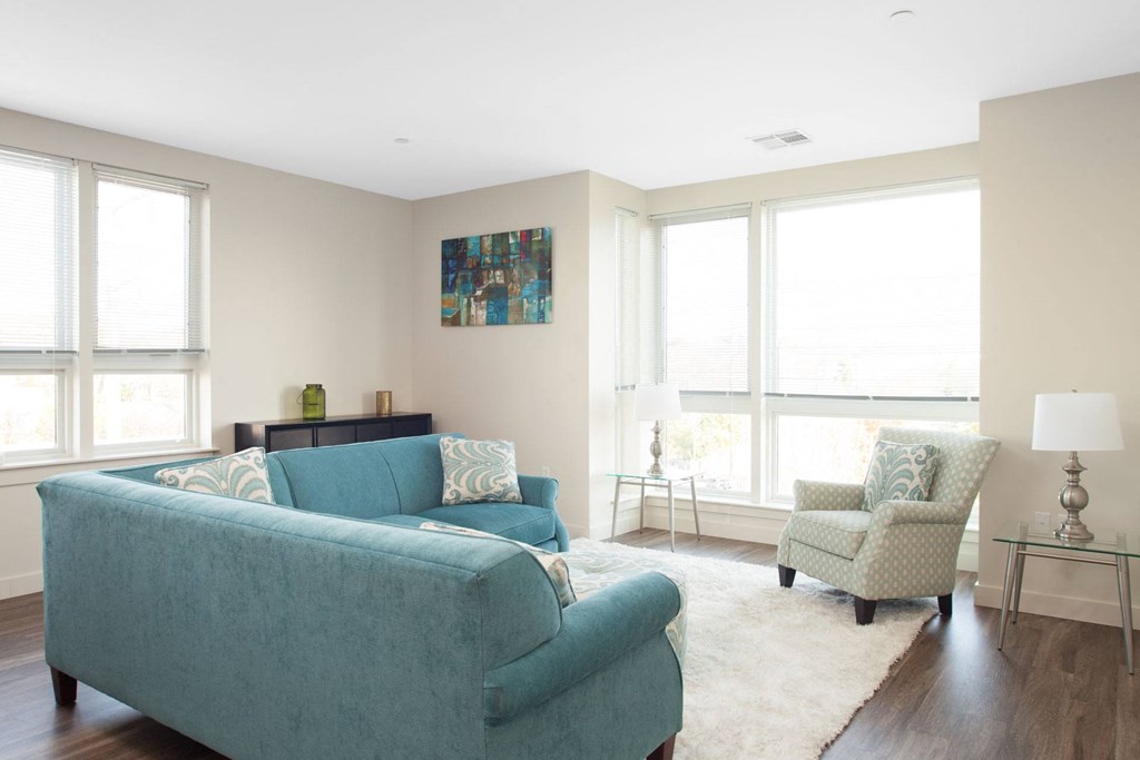 A living room with a blue couch and a painting on the wall.