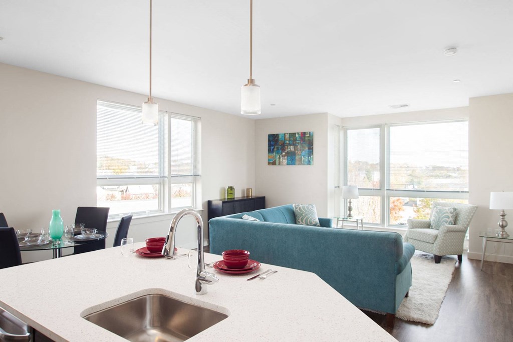A kitchen with a white counter top and a blue couch in the background.