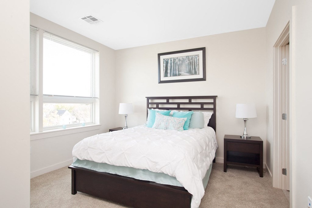 A bedroom with a large bed and a picture frame on the wall.