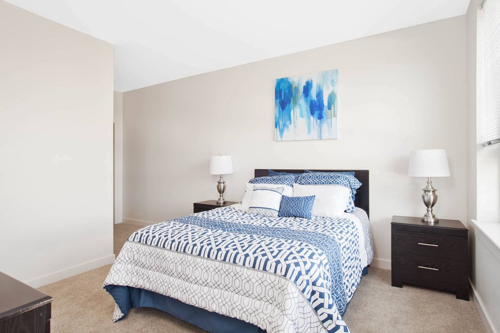 A bedroom with a bed, nightstands, and a painting on the wall.