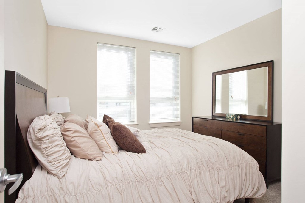 A bedroom with a bed, nightstand, and mirror.