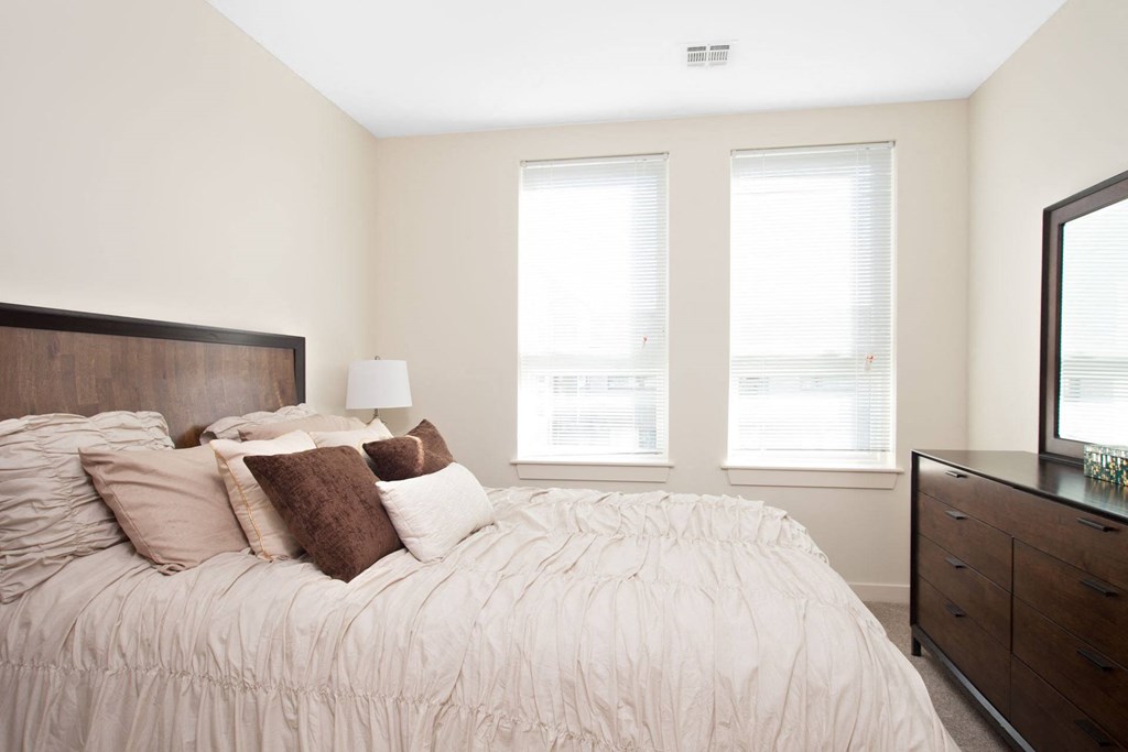 A bedroom with a bed, nightstand, and window.