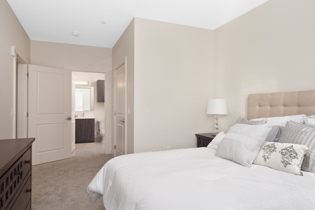 A bedroom with a large bed and a nightstand with a lamp.