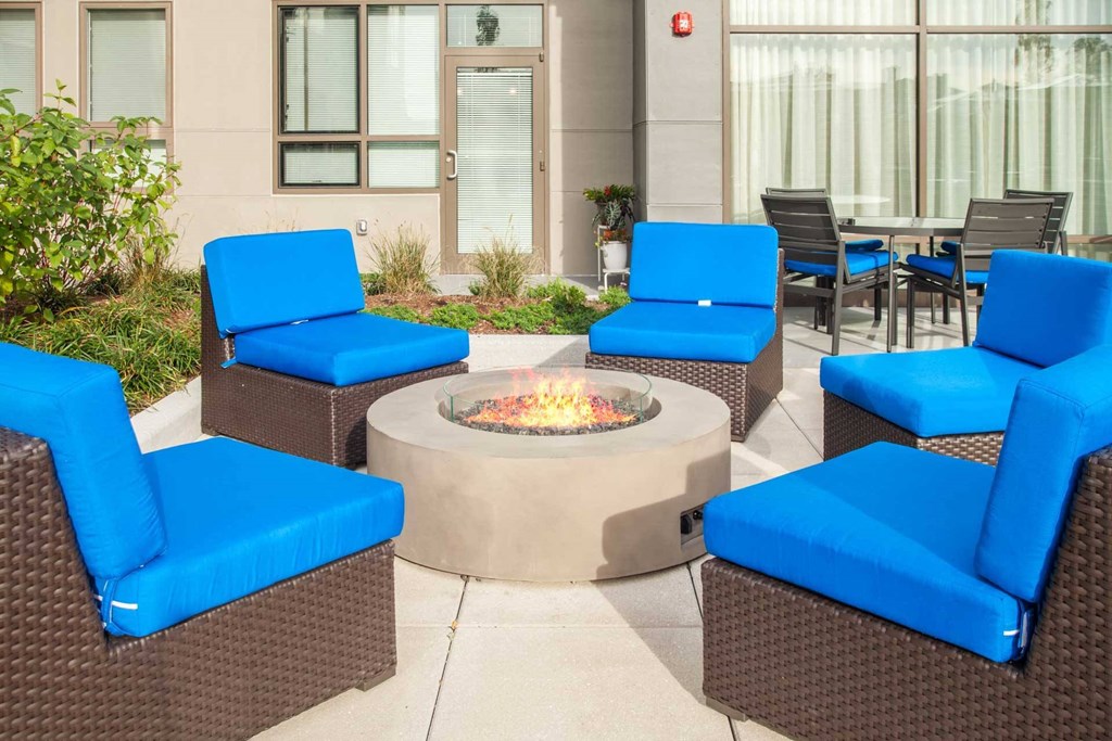 A patio with blue chairs and a fire pit.