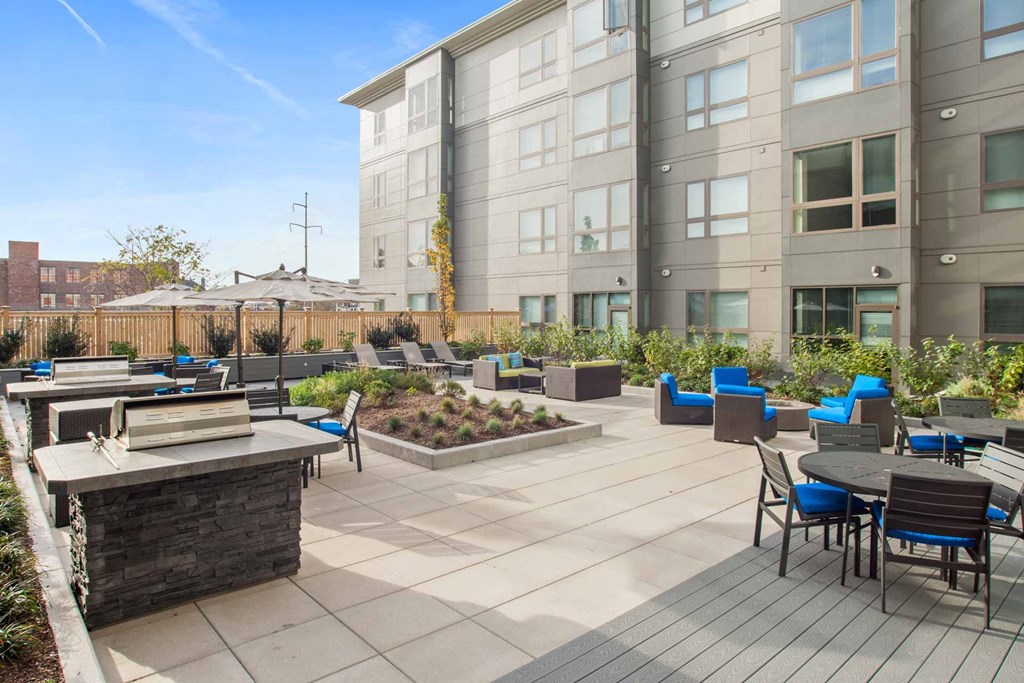 A patio with a table and chairs is surrounded by a building and a fence.