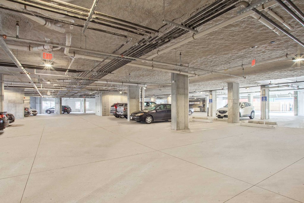 A spacious parking garage with concrete floors and multiple cars parked.