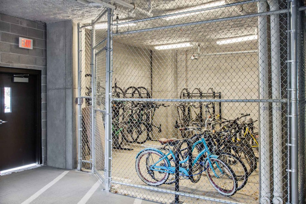 A bike rack with bikes inside a fenced area.