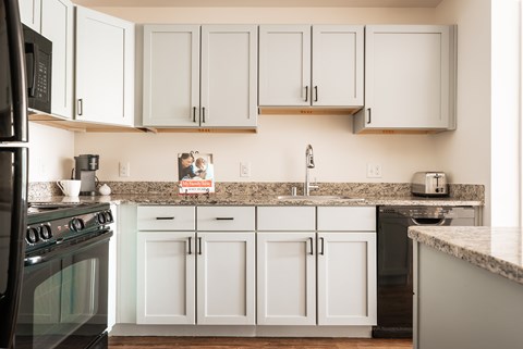 A kitchen with white cabinets and a black stove top.