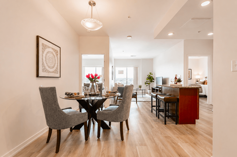 A dining room with a table set for four and a chandelier hanging from the ceiling.