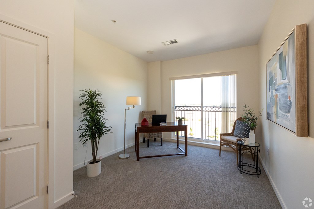 an office or second bedroom with desk chair and large window