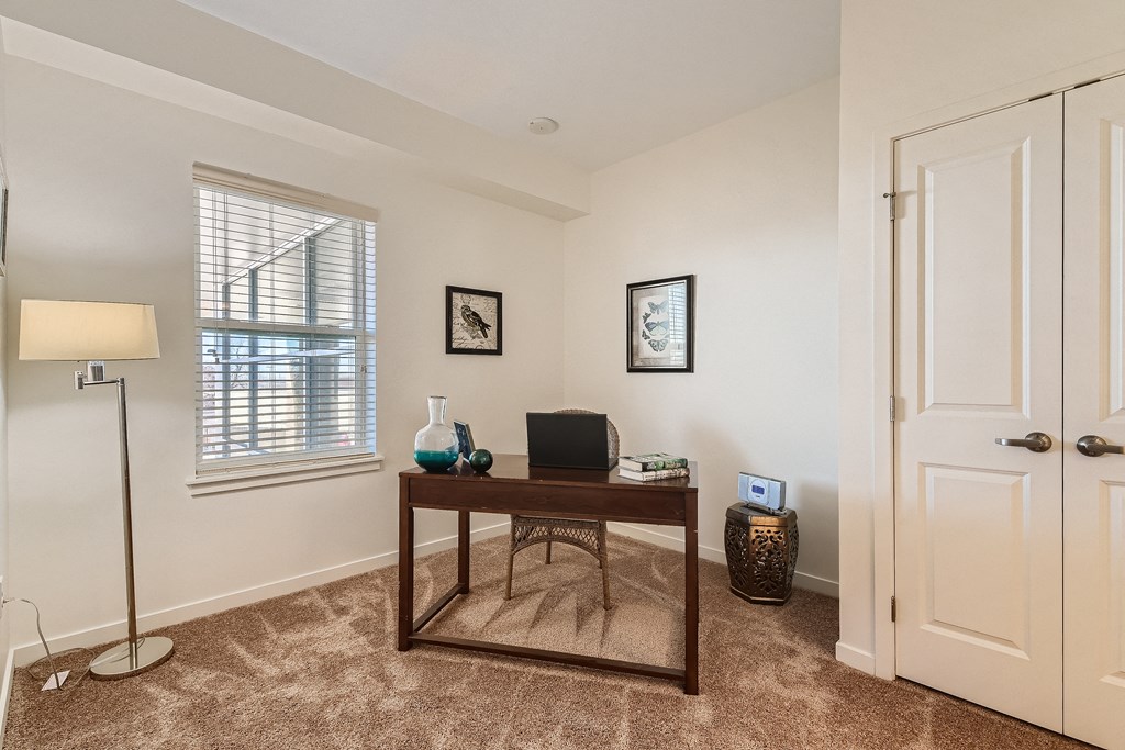 a living room with a desk and a window