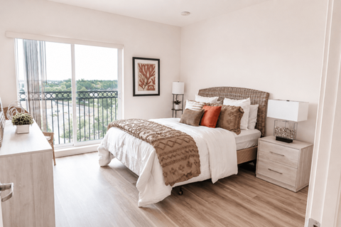 A bedroom with a large bed and a view of the balcony.
