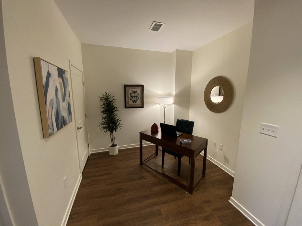 a living room with a wooden floor and a desk with a laptop