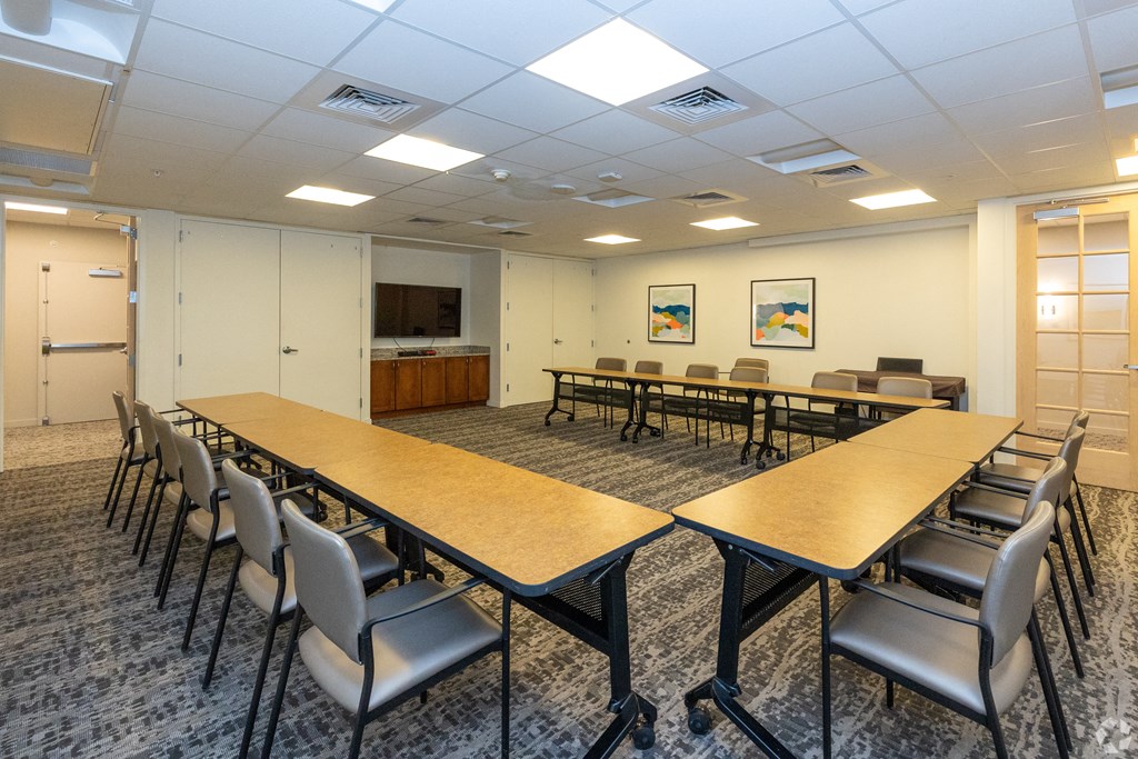 a community room with tables and chairs and a tv in the corner