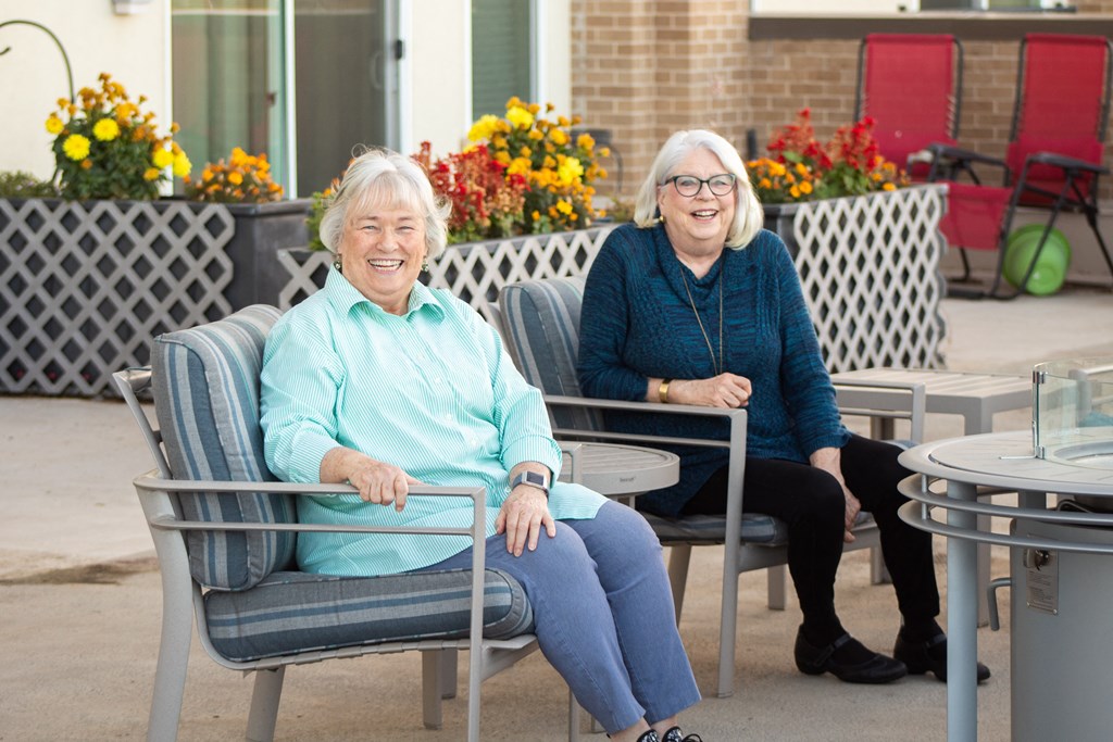 two older women sitting in chairs in a courtyard