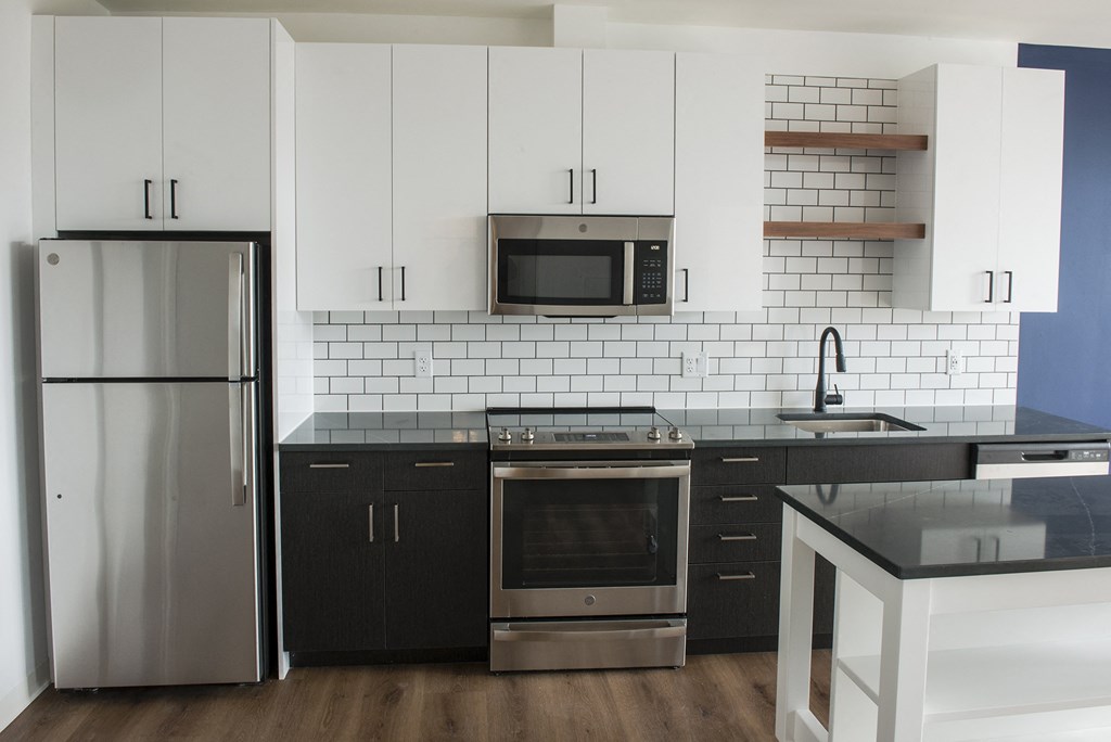 a kitchen with black and white cabinets and stainless steel appliances