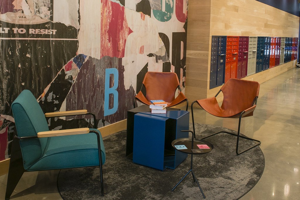 a group of chairs and a table in the lobby of a building with a mural