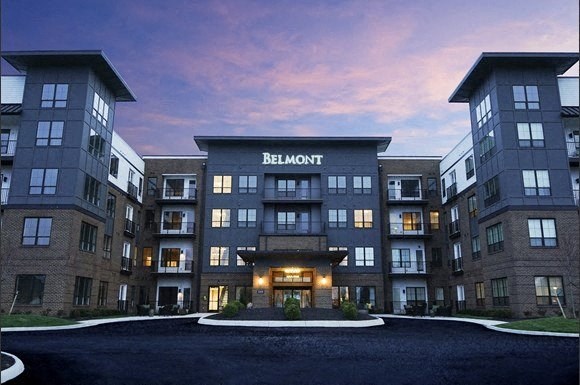 an apartment building at dusk with the facade lit up and the name of the building
