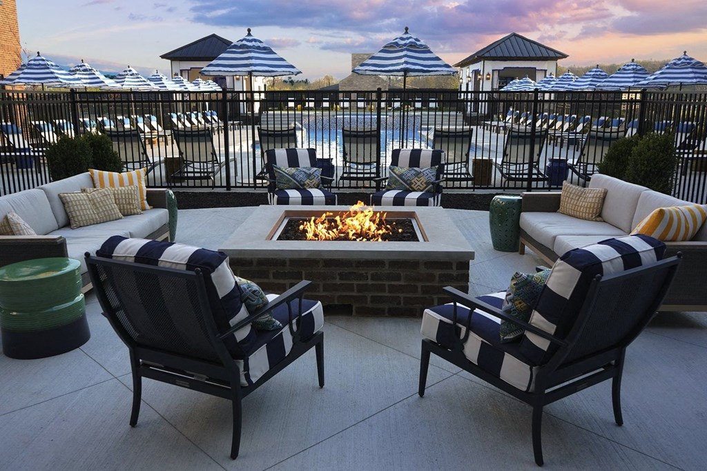 a fire pit on a patio with chairs and umbrellas
