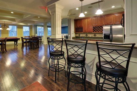 a large kitchen with bar stools and a dining area