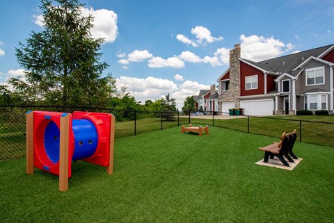 a yard with a playground and two benches in front of a house