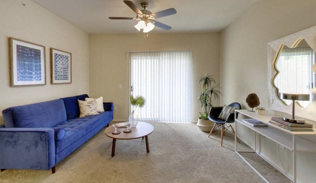 a living room with a blue couch and a ceiling fan