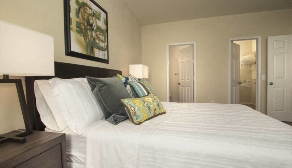 a bedroom with a white bed and a painting on the wall