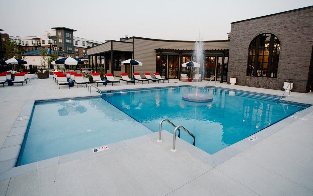 a swimming pool with chairs around it in front of a building